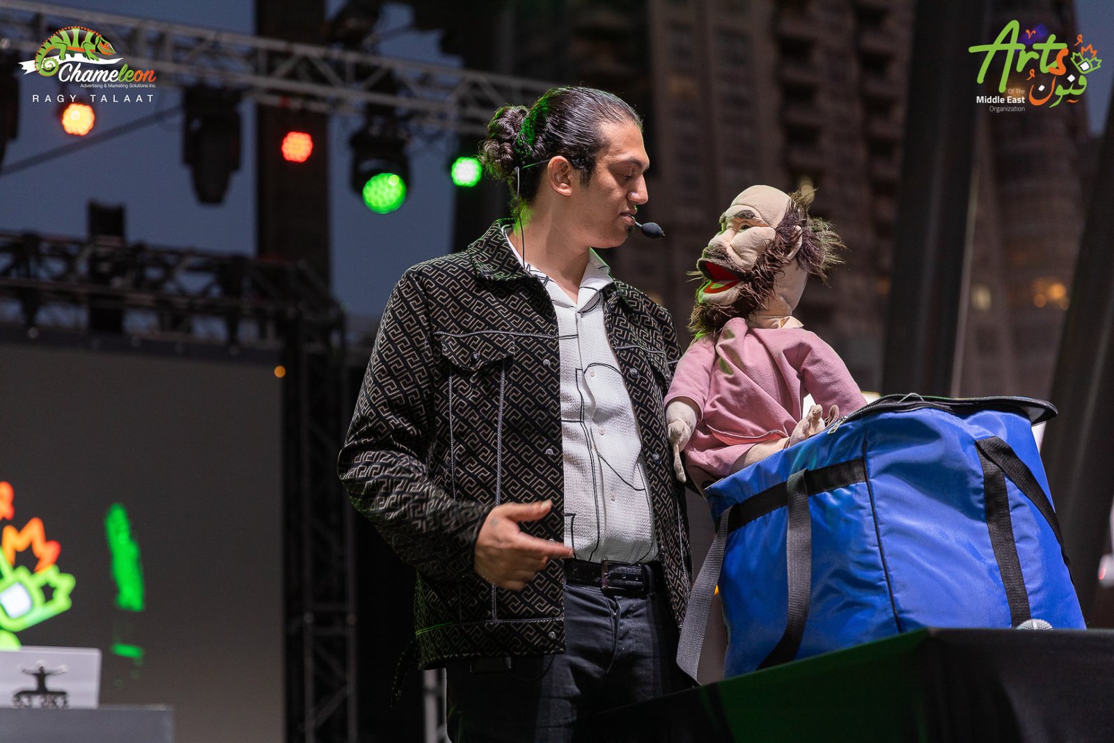 Abanob Flex in conversation with a puppet under stage lights