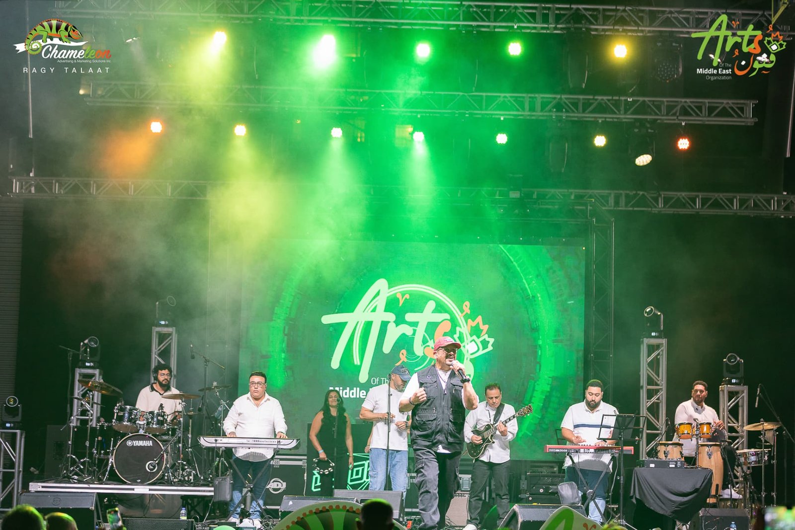 The full band performing under green stage lights