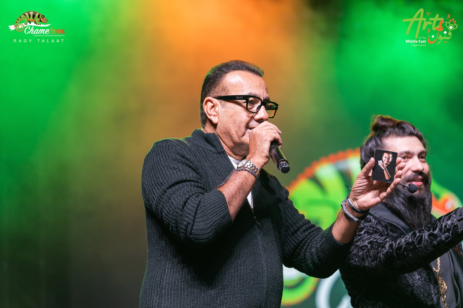 Osama Mounier performing beside the host against a green and orange backdrop